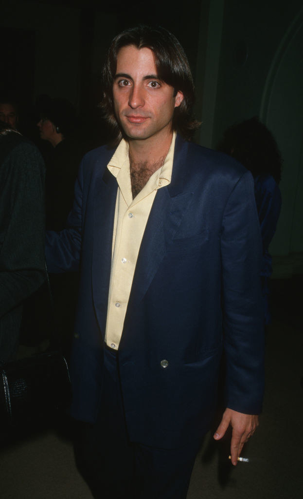 A young Andy Garcia holding a cigarette and looking at the camera