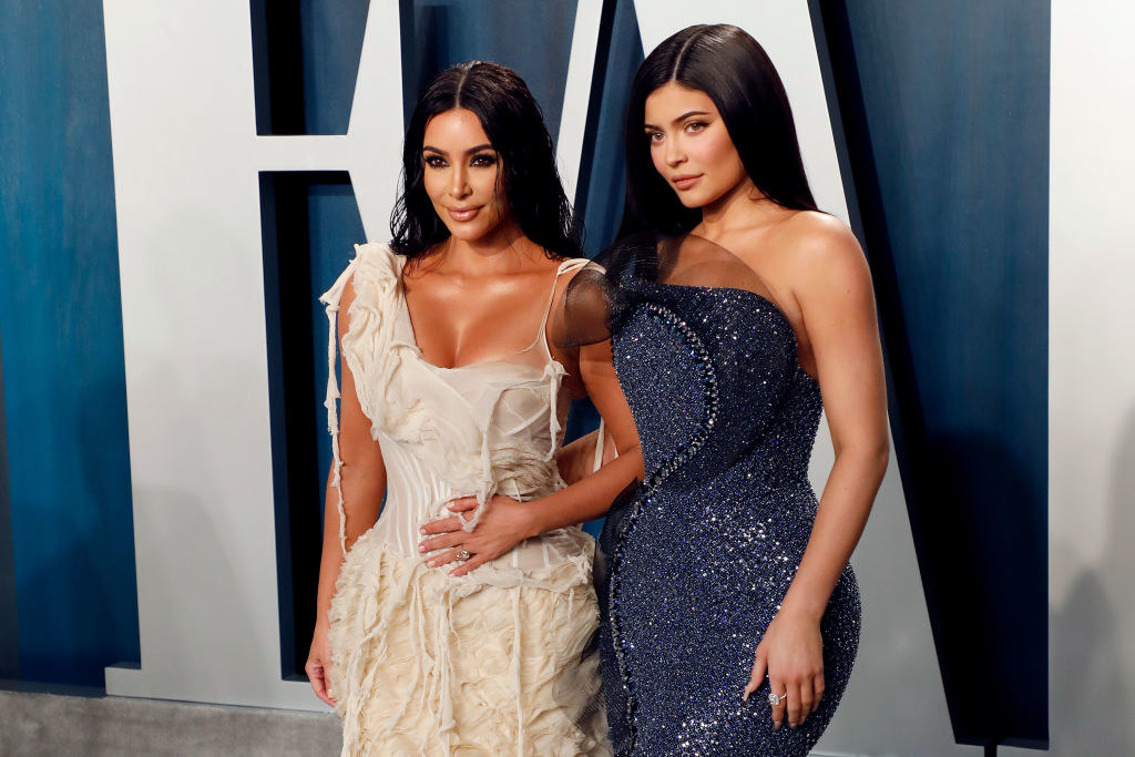 Kim and Kylie stand together wearing tight dresses