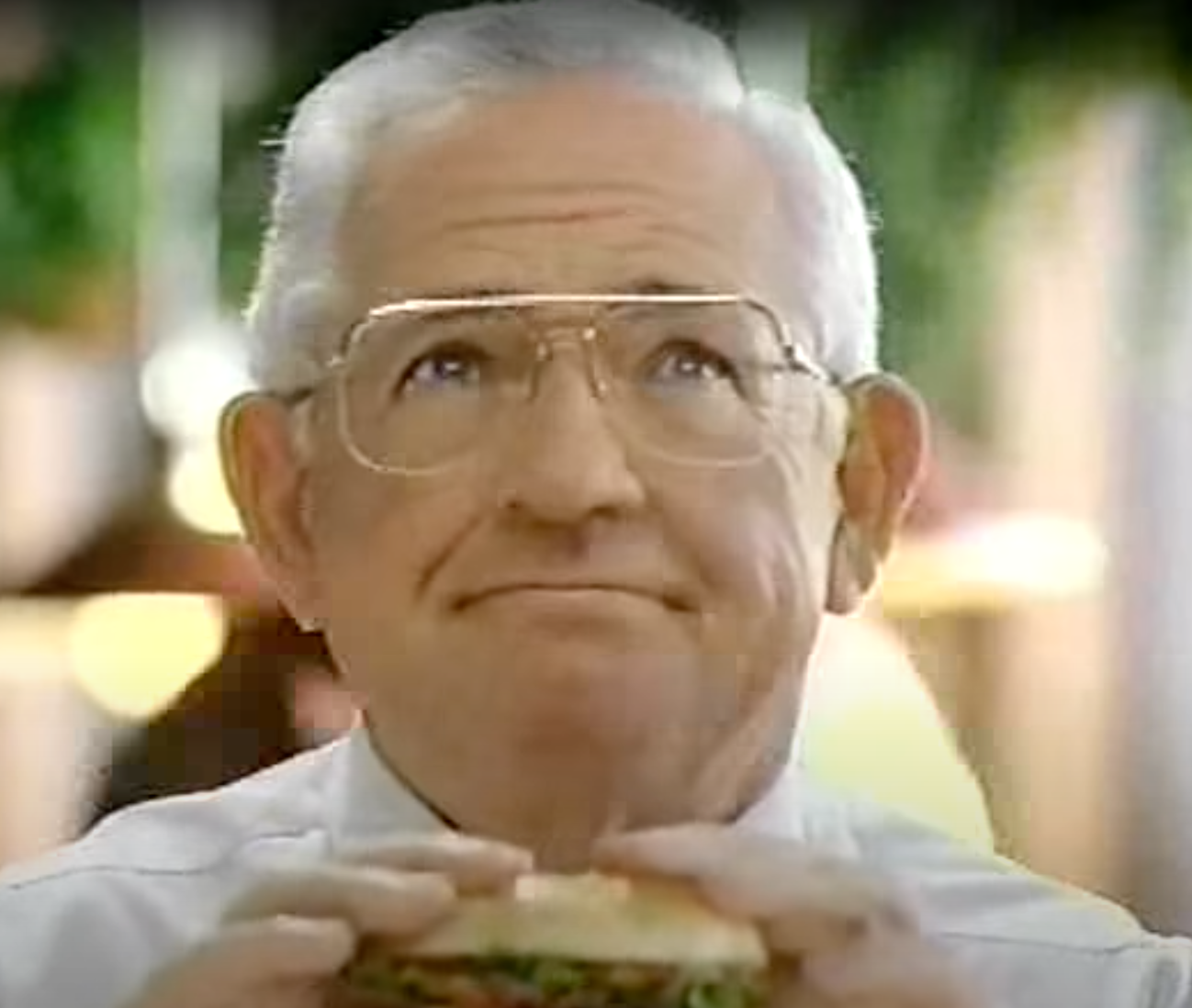 Dave Thomas holding a burger in his hands and smiling