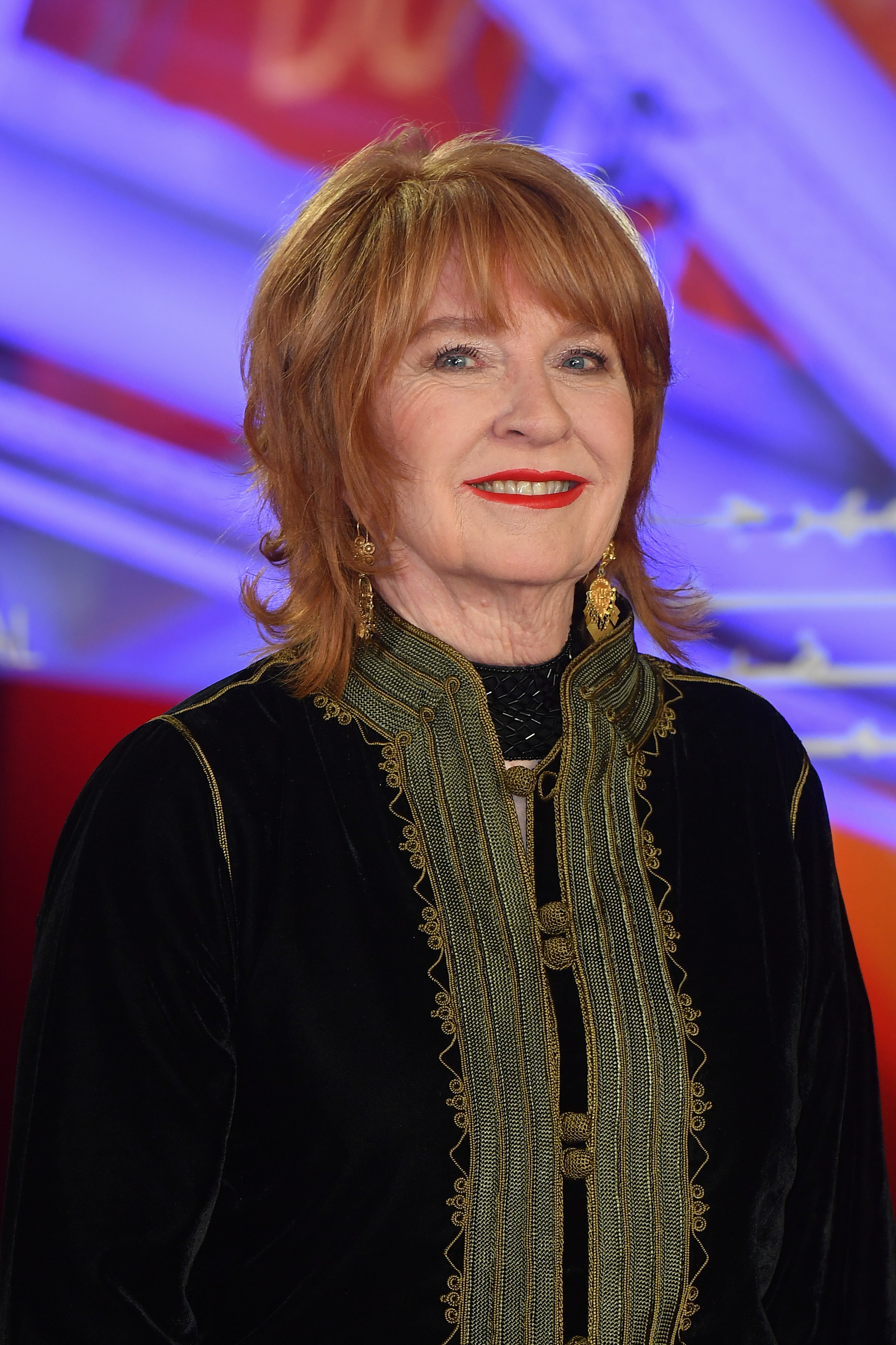 Jan Chapman smiling in a black jacket with gold details