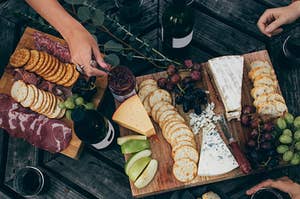 bottles of wine surrounded by beautiful boards of meat and cheese