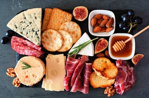 a charcuterie board with crackers, brie cheese, honey, almonds, and meat