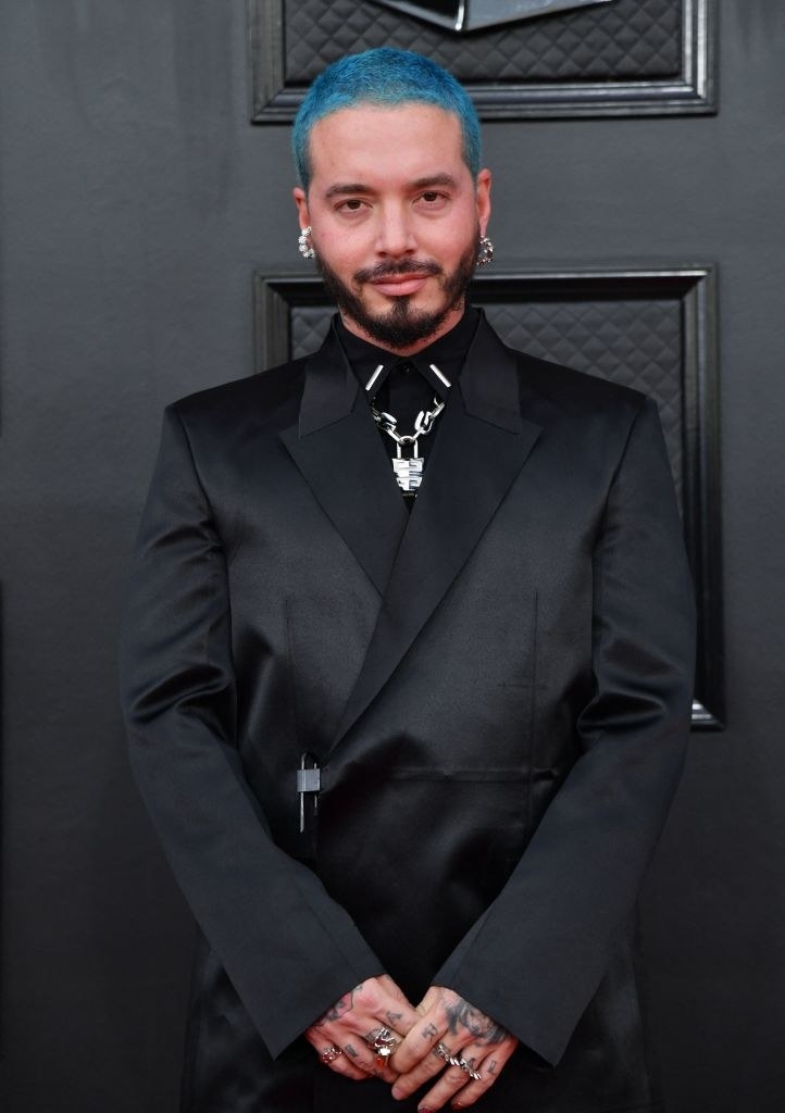 J Balvin looking serious and standing against a door