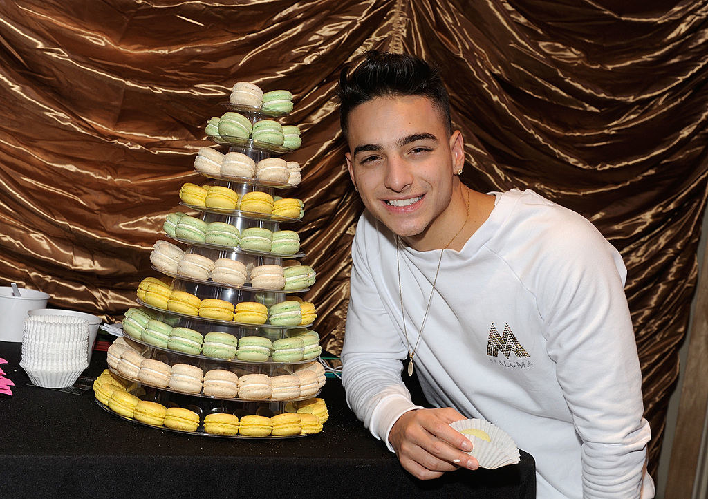 Maluma smiling next to a tray of macarons
