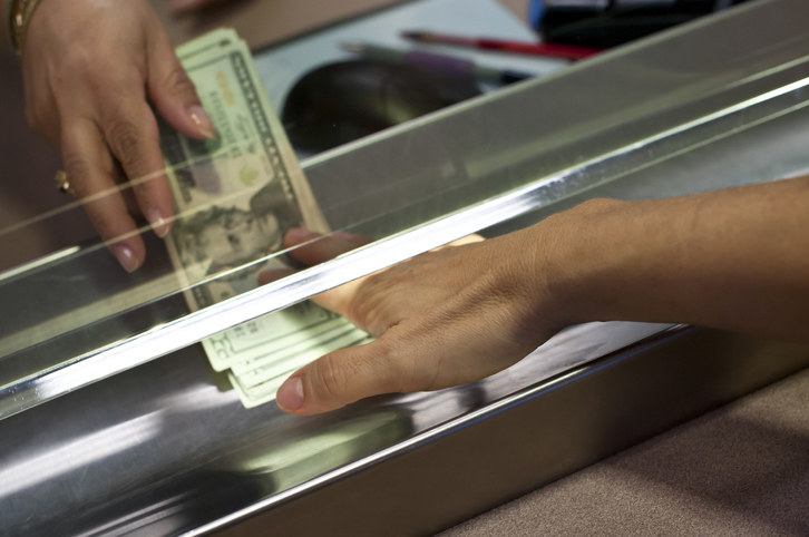 Hands passing money at a bank teller window