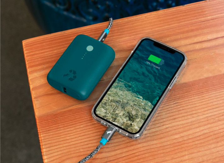 Phone charging on wooden table next to turquoise portable charger