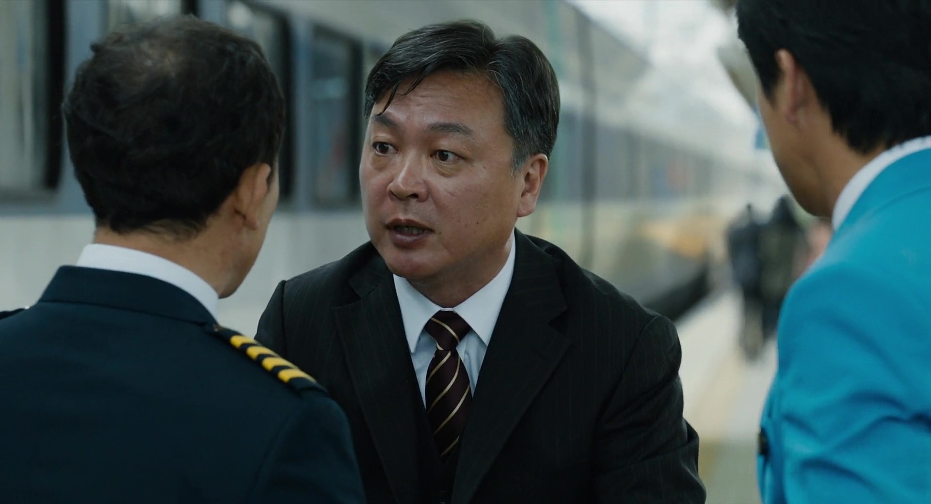 Kim Eui-sung talking to a man next to a train