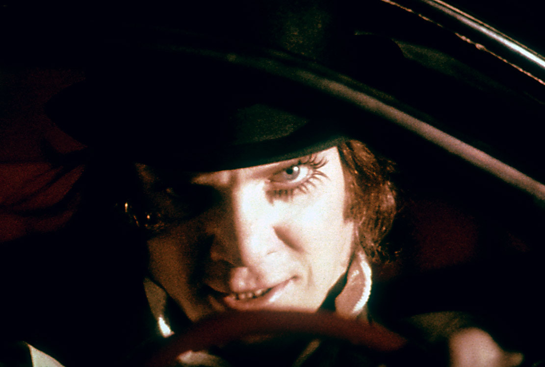 Alex from &quot;A Clockwork Orange&quot; smiling and peeking out from under the brim of his hat