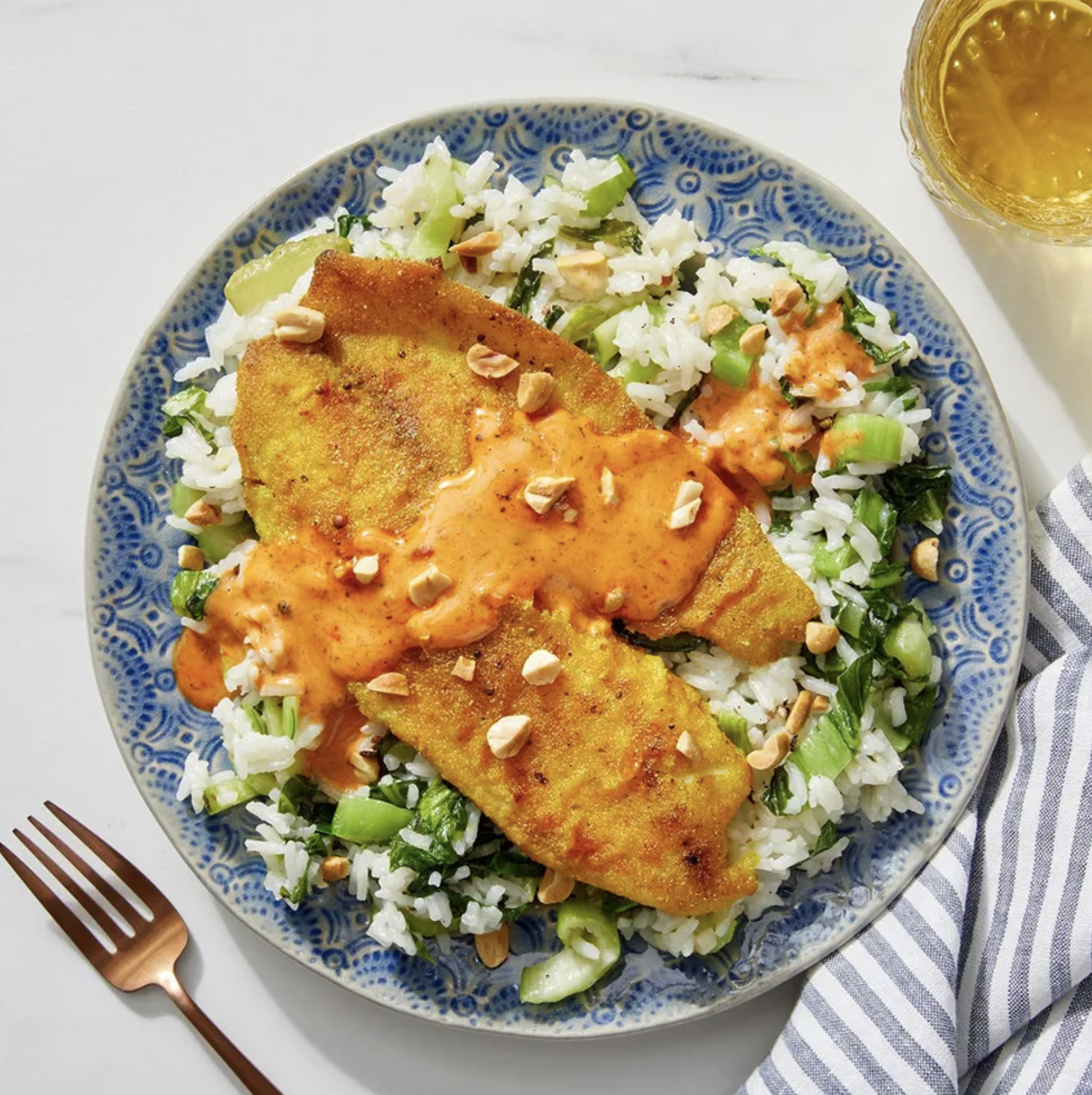 Tilapia drizzled with creamy sauce over a bed of rice and bok choy