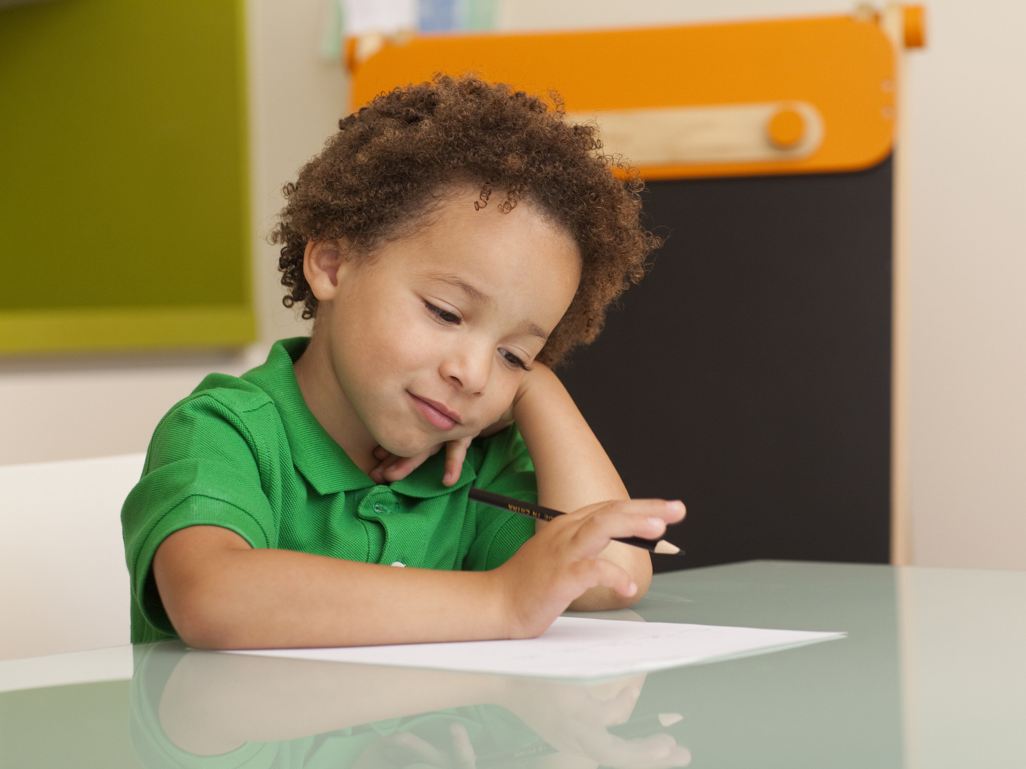 A small child sitting at a table with a pencil and paper