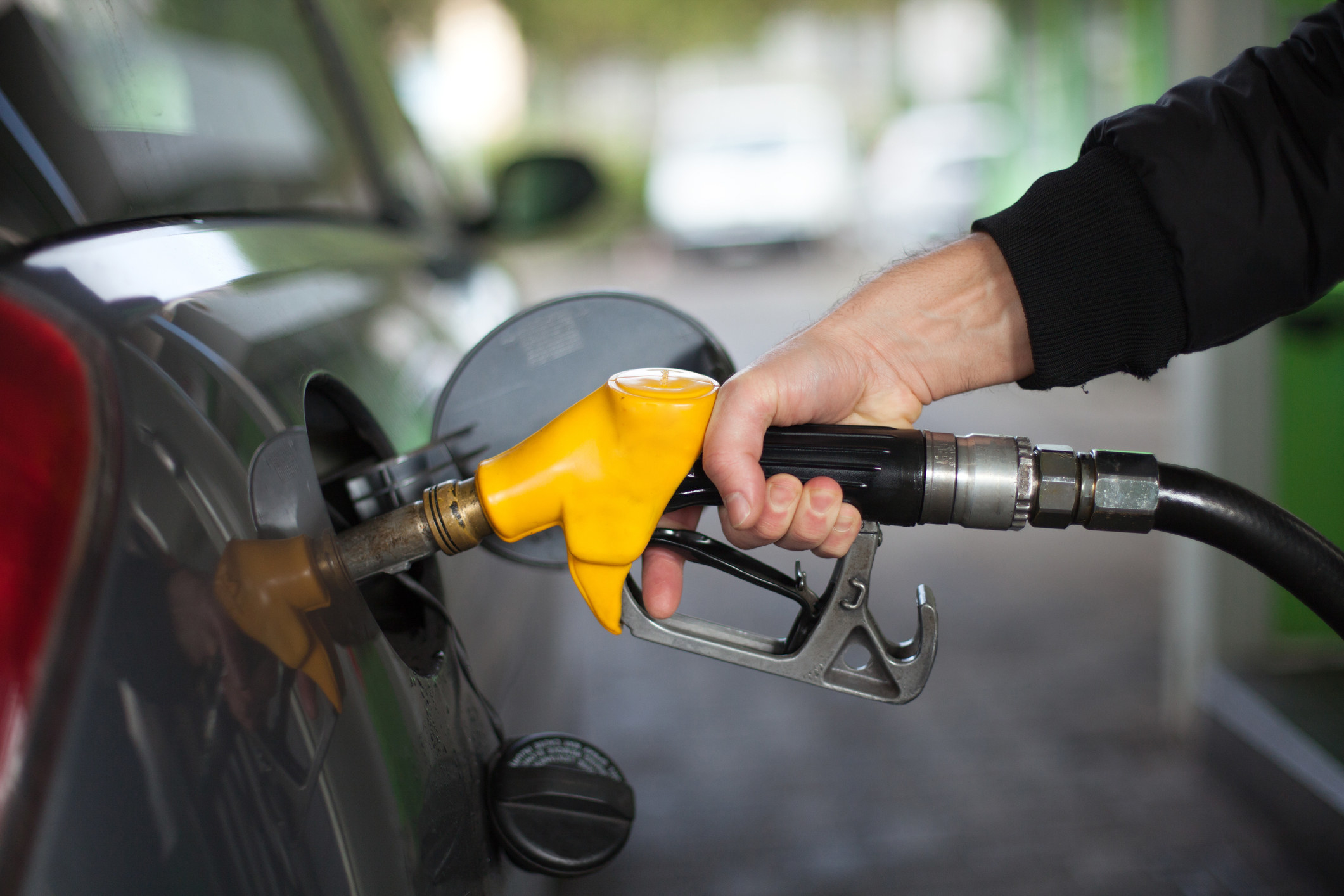A person&#x27;s hand pumping gas into a car
