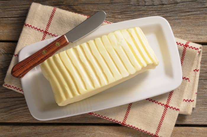 A plate of butter with a knife.
