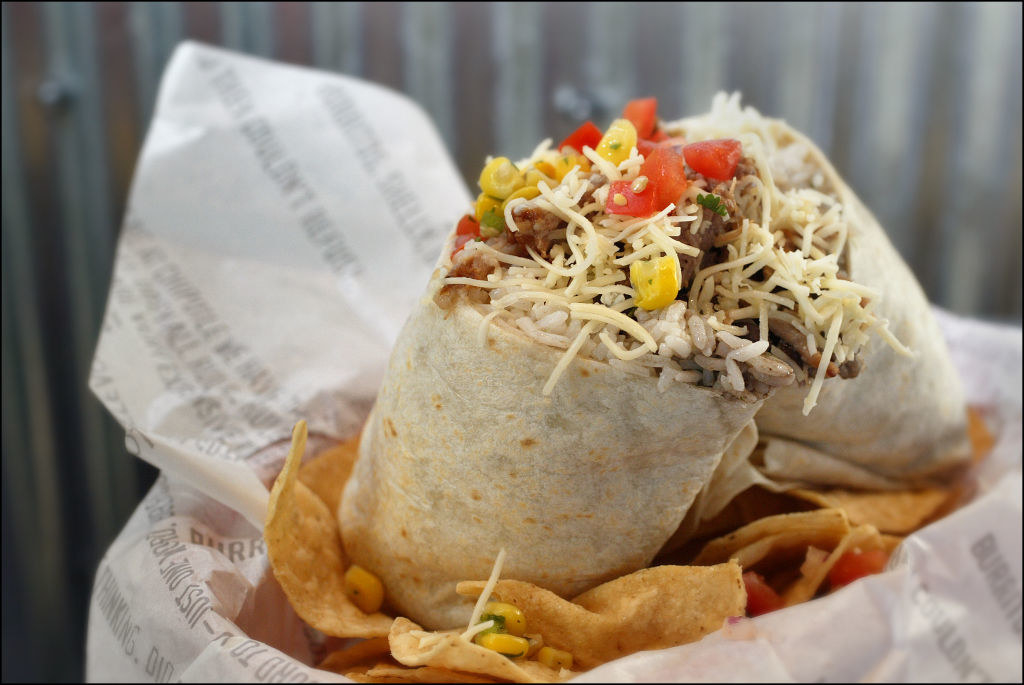 A burrito surrounded by tortilla chips.