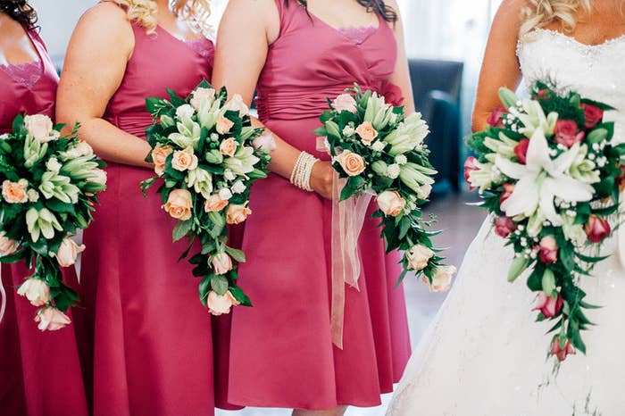 Three bridesmaids with matching dresses and bouquets standing beside a bride