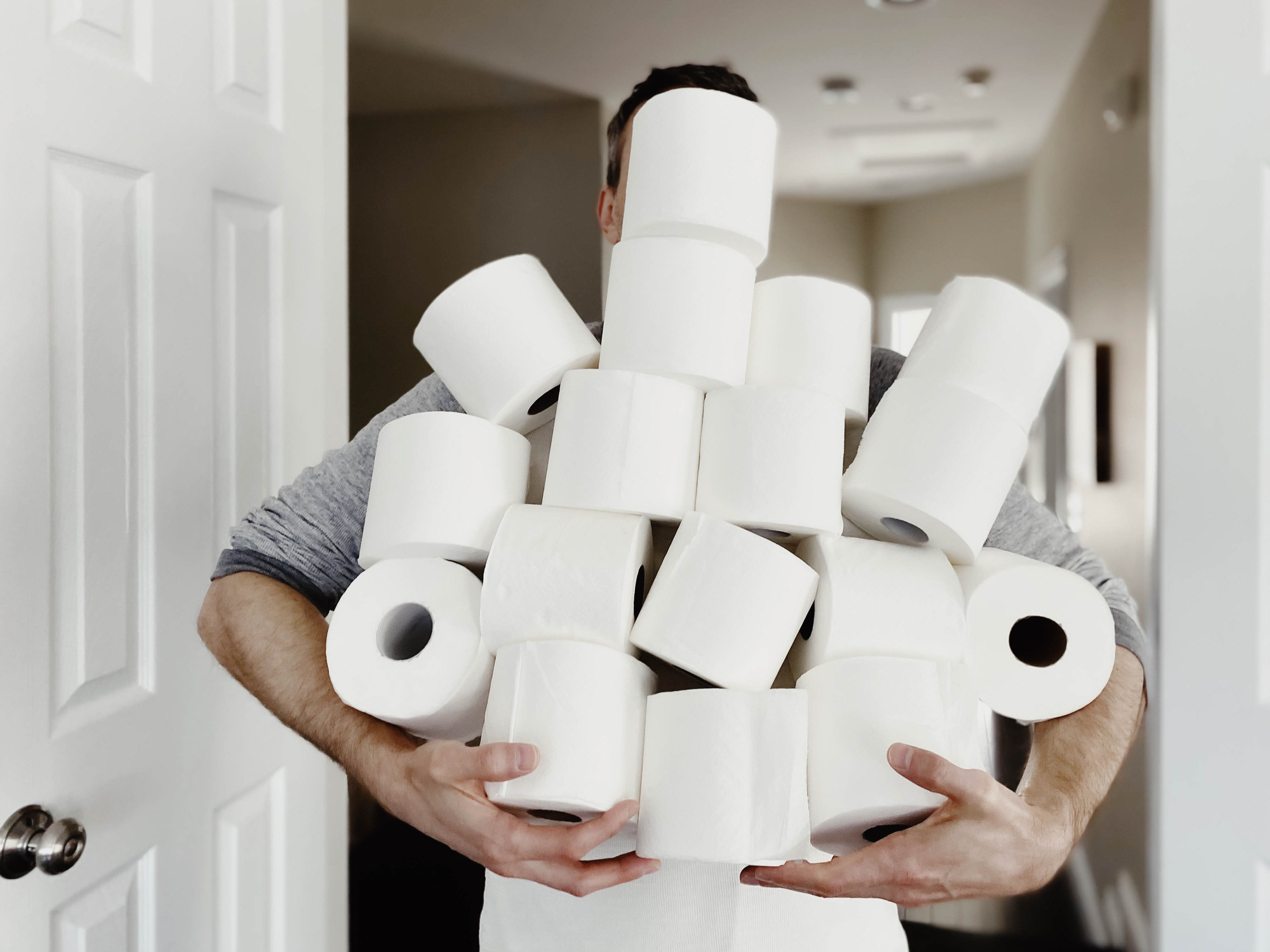 A man holding many rolls of toilet paper.