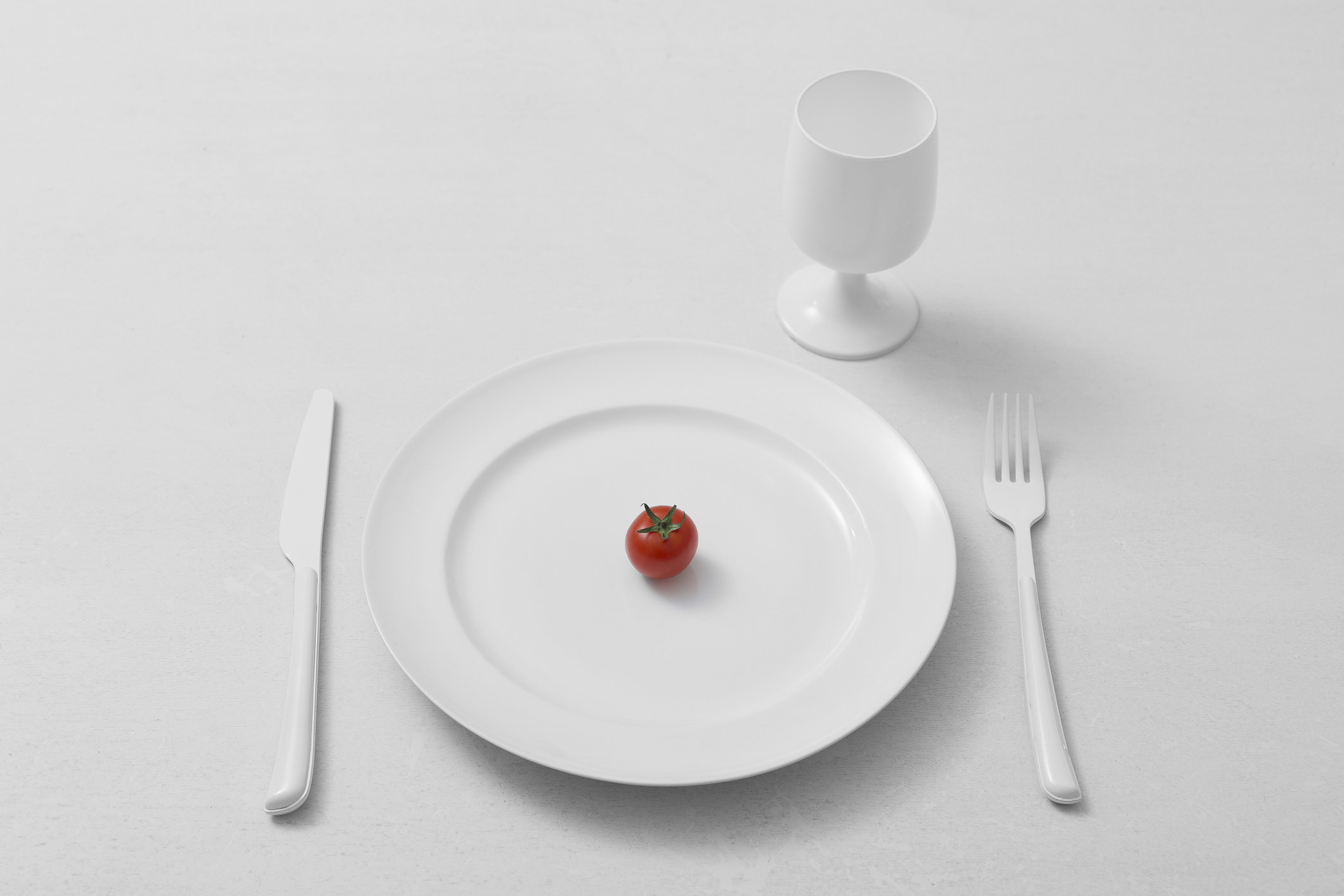 A plate with a single cherry tomato.
