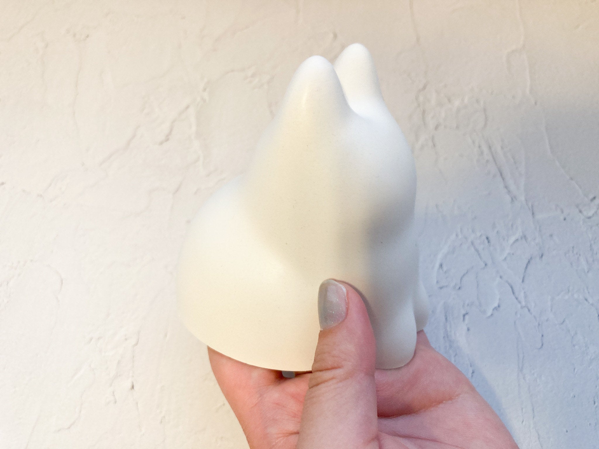 手に持たれた無表情のネコ型オブジェクト。