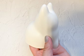 手に持たれた無表情のネコ型オブジェクト。