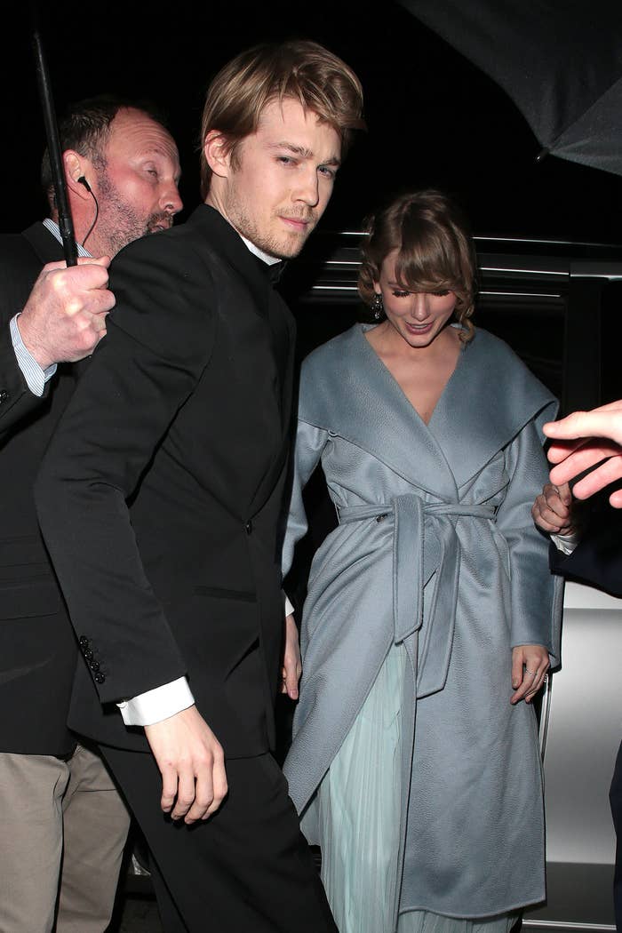 Joe and Taylor walk outside as someone holds an umbrella
