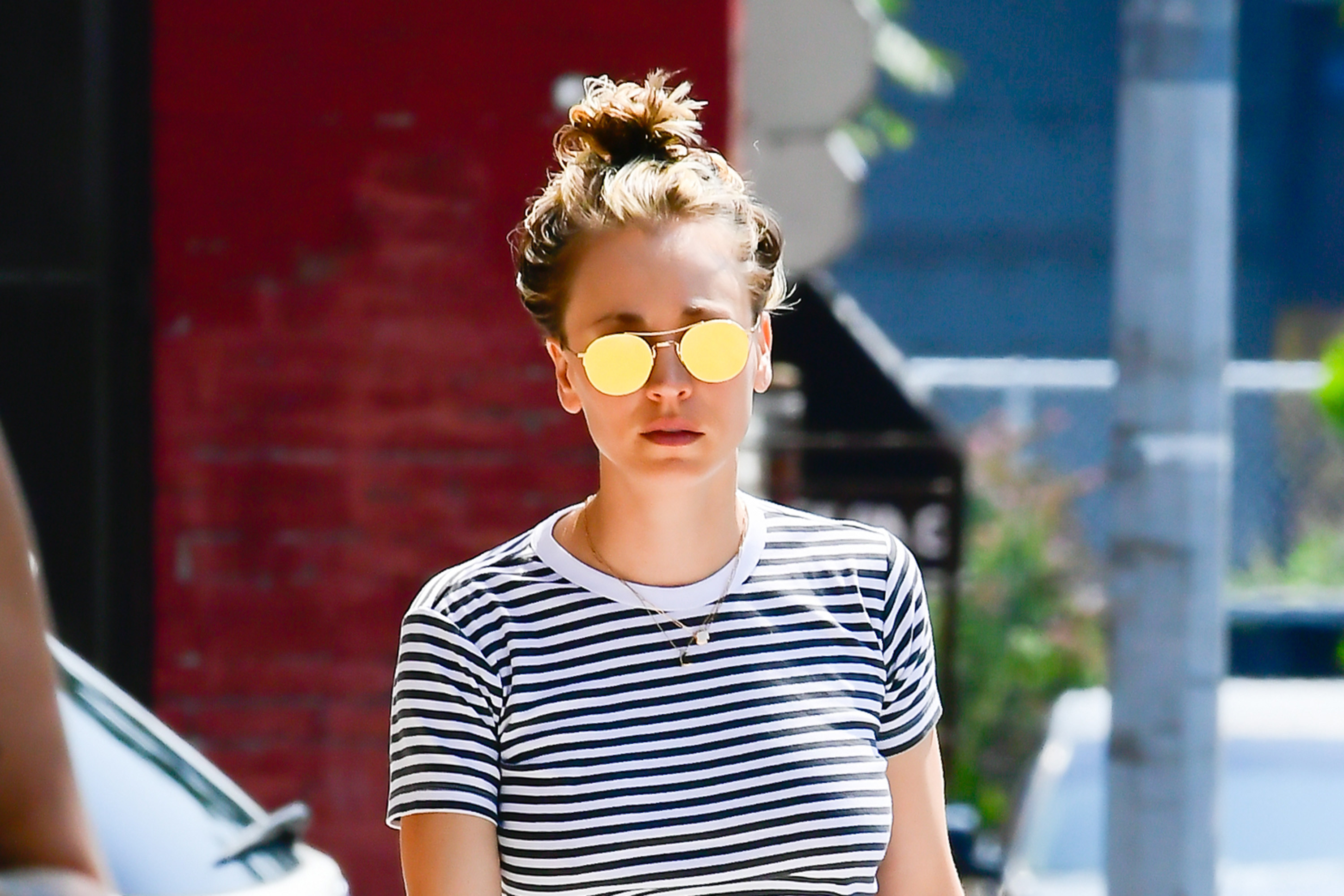 Kaley walks down the street in sunglasses and a striped shirt