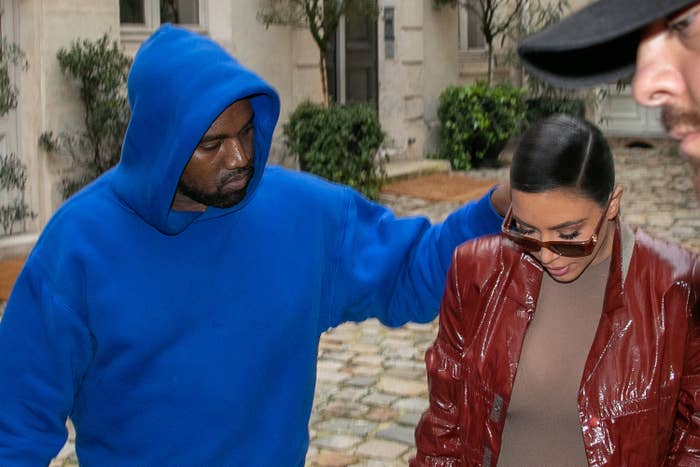 Kanye puts his arm around Kim while walking down the street