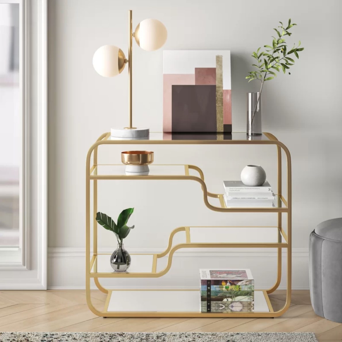 a gold mirrored console table decorated with plants and art
