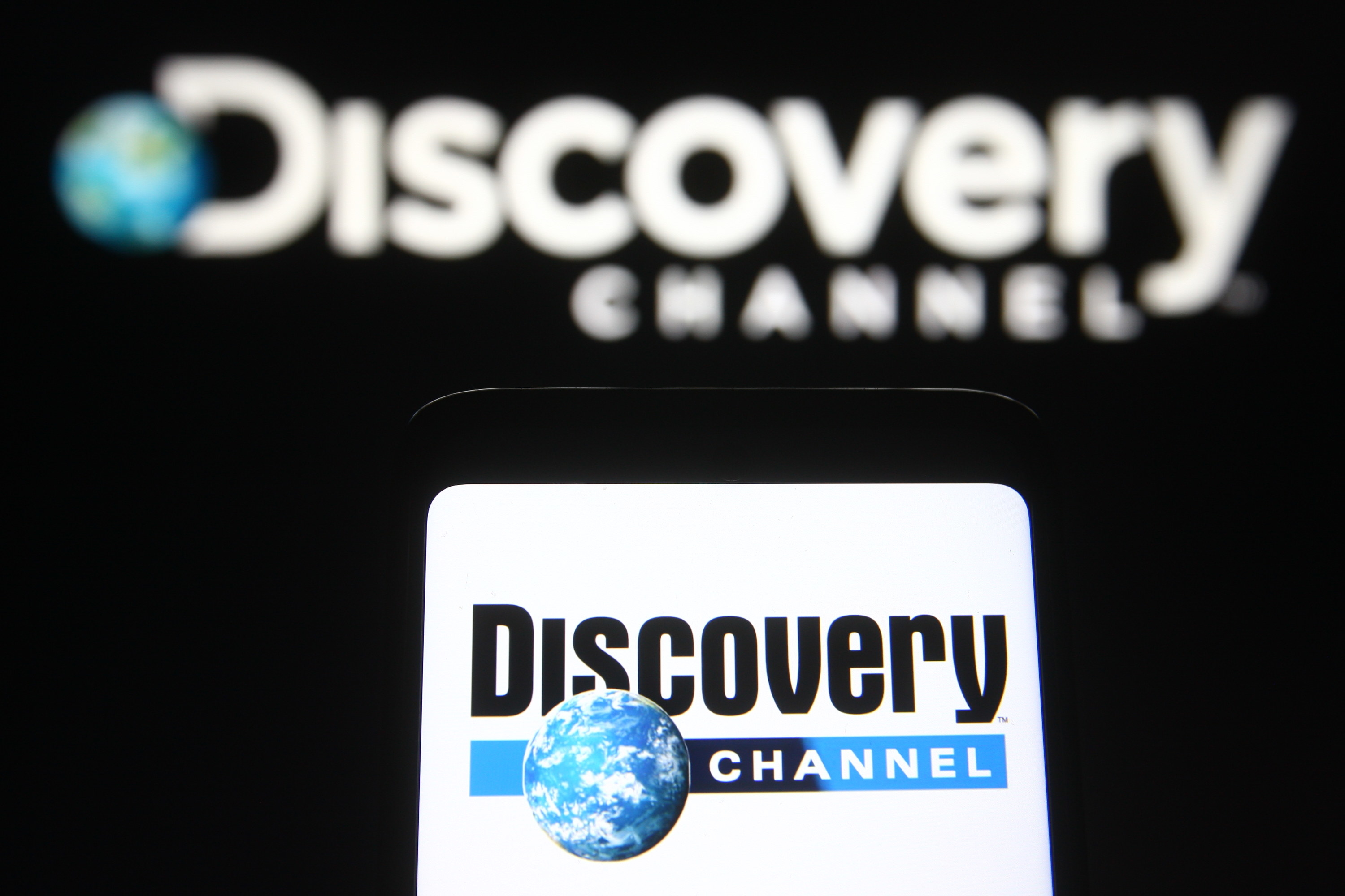 The Discovery Channel logo shown on a smartphone and a PC screen