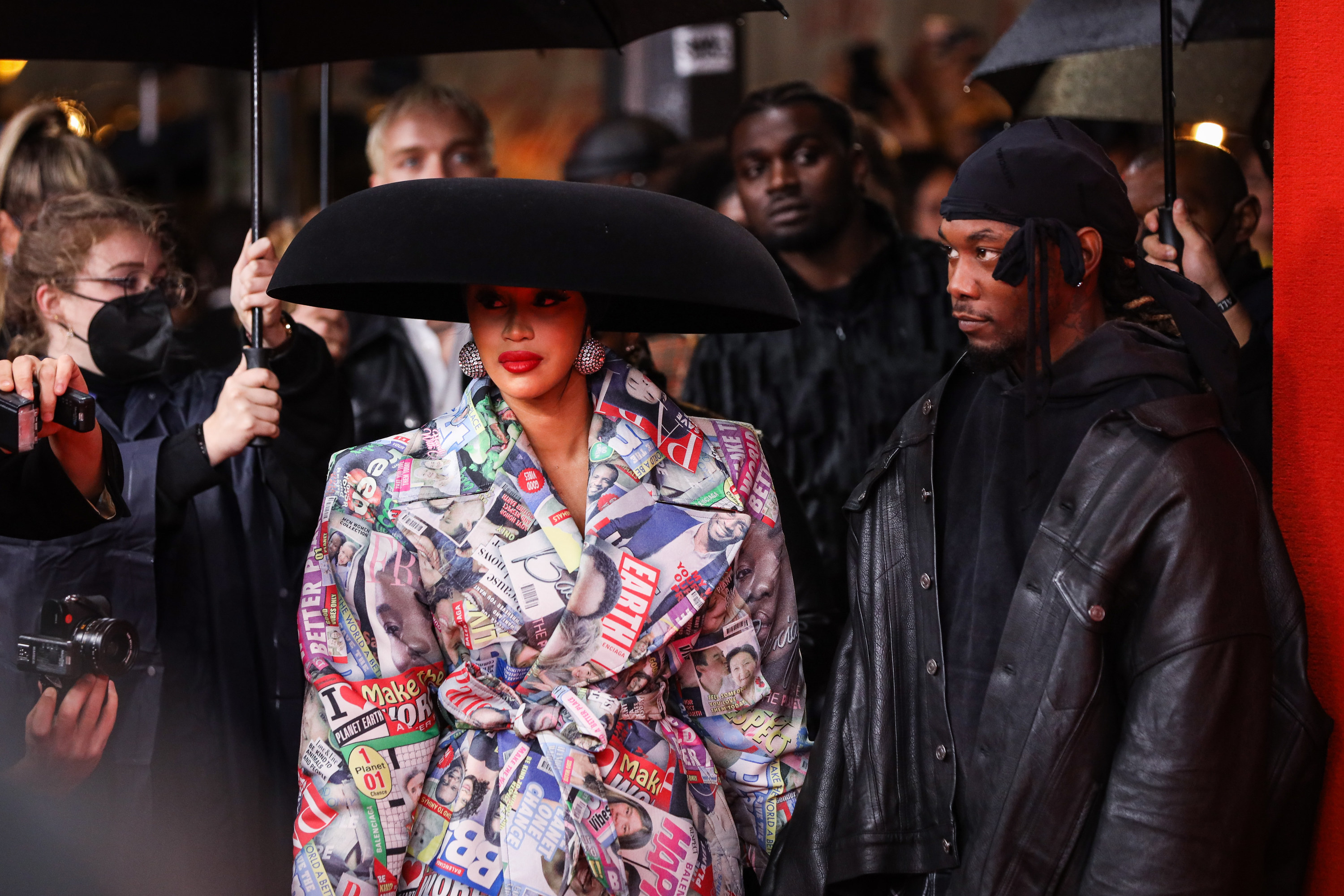 Cardi B and Offset standing under umbrellas and surrounded by a crowd of people
