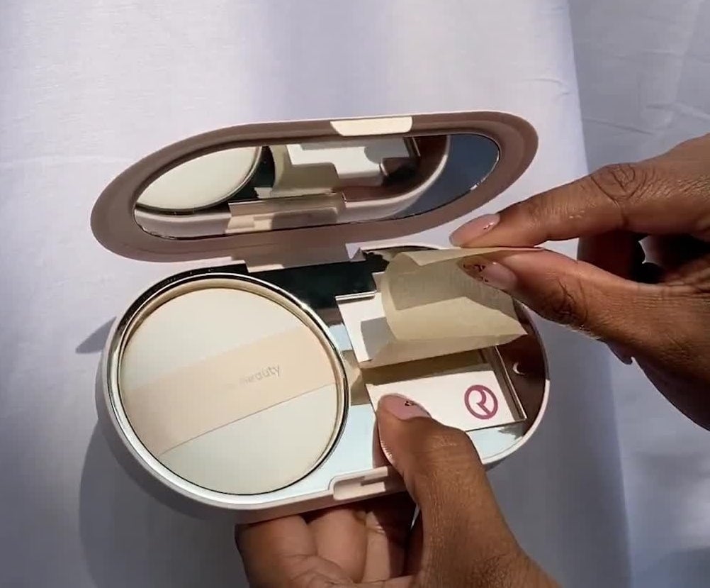 a person removing a blotting tissue from the makeup compact