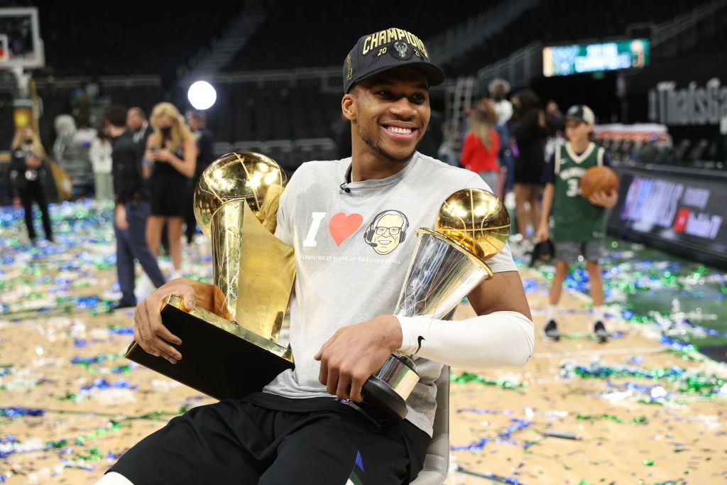 Giannis holding two large trophies