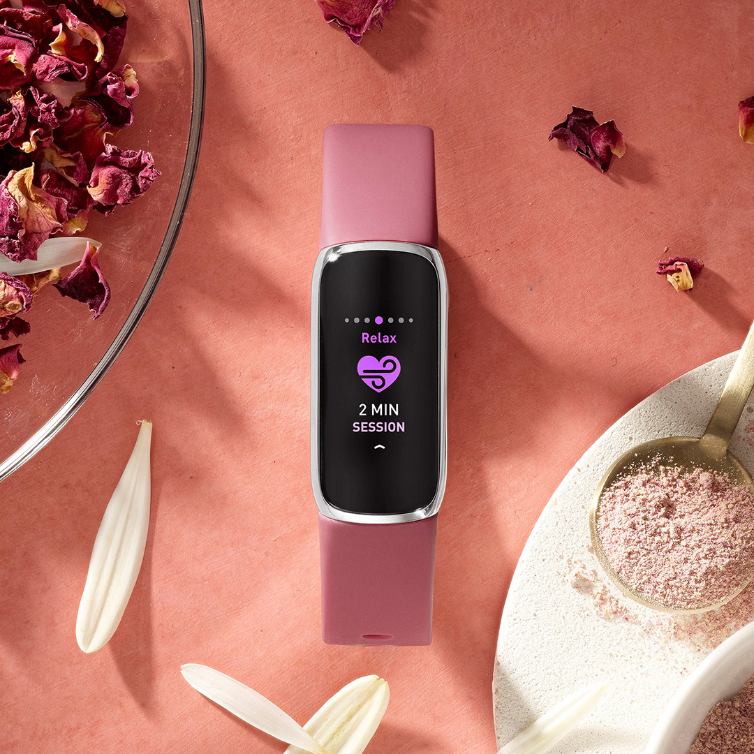 The fitbit on a table surrounded by flower petals