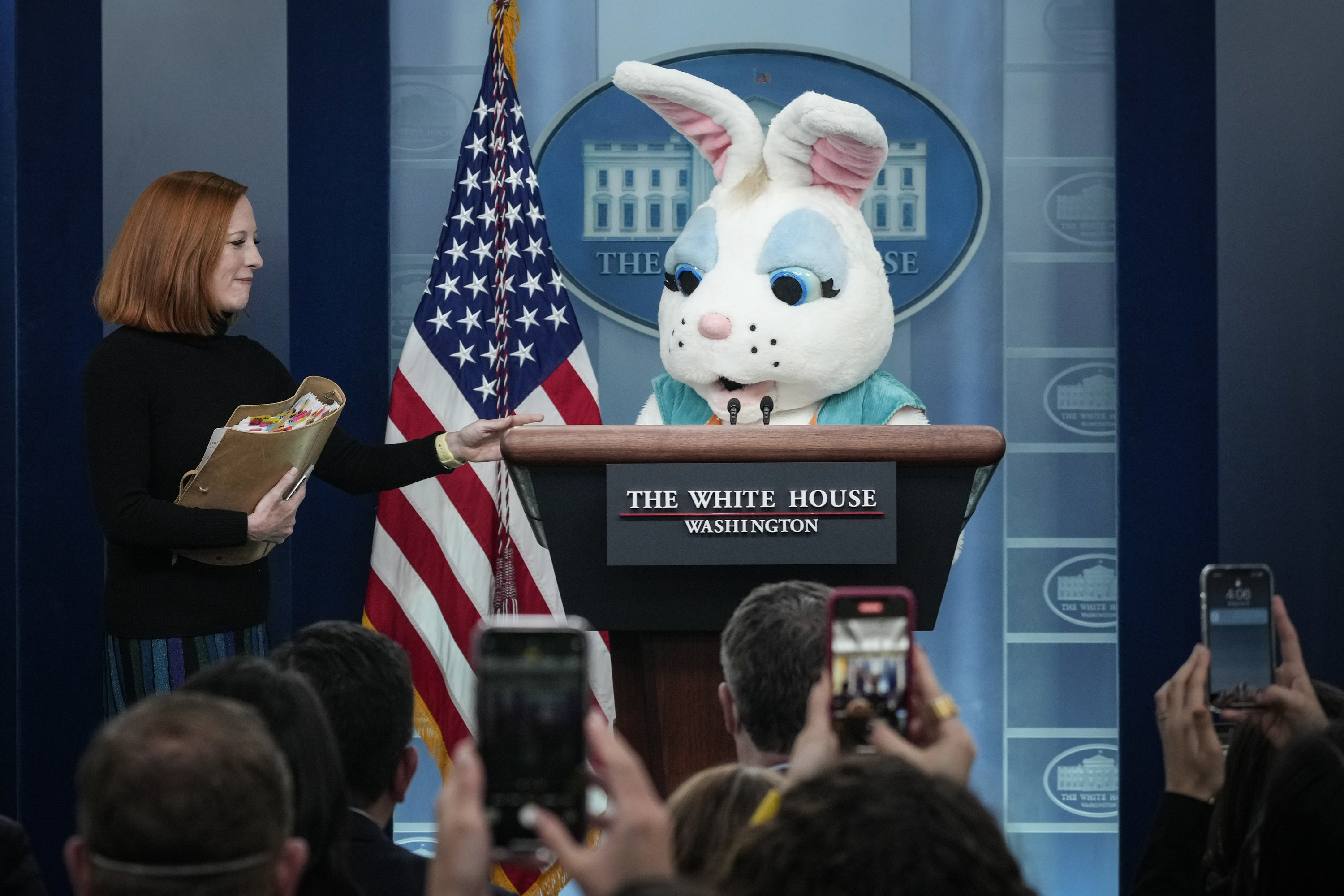 Jen Psaki is shown next to a bunny behind the podium