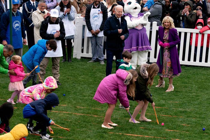 Joe and Jill Biden smile as children roll painted eggs along the lawn with wooden spoons