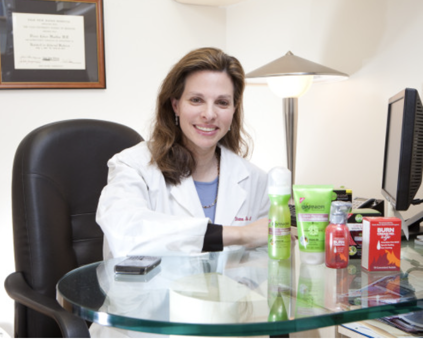 A female doctor sitting at a desk in her labcoat