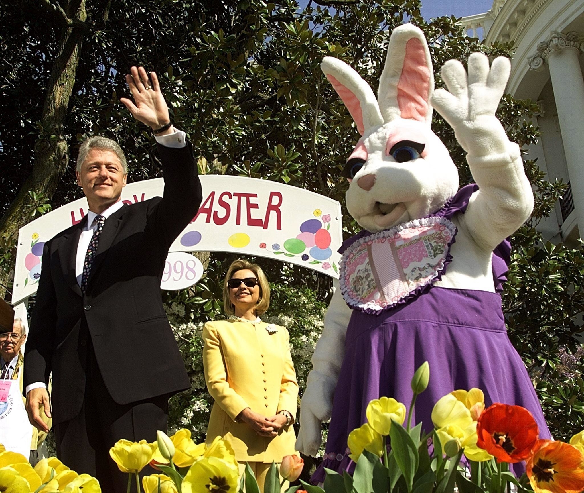 Pink Bunny wears the same purple dress and waves next to Bill and Hillary Clinton