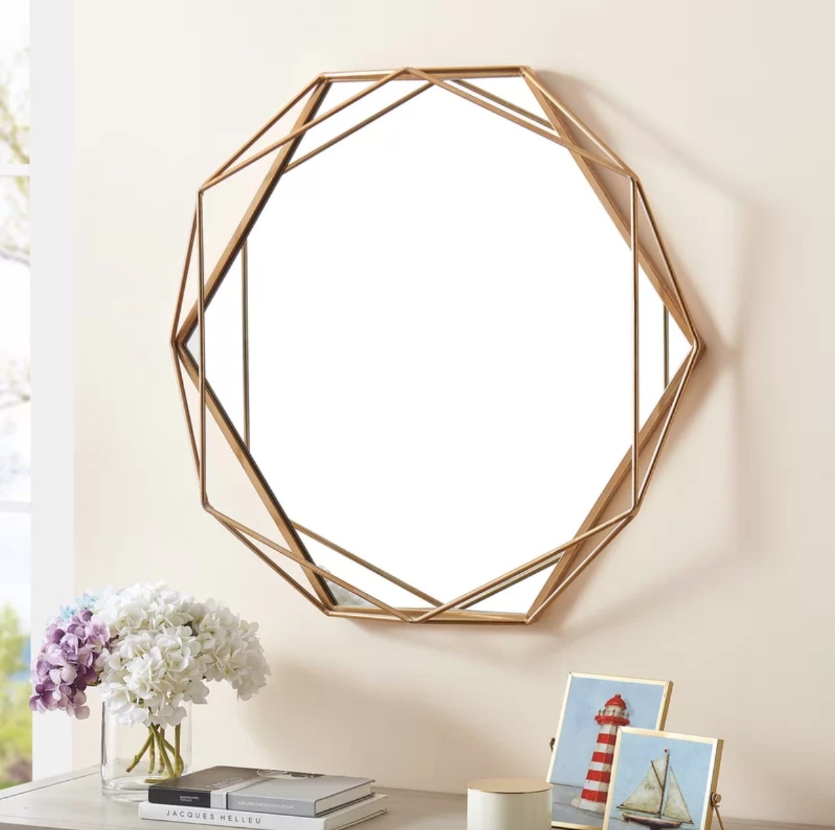 a gold geometric mirror hanging over a decorated table top
