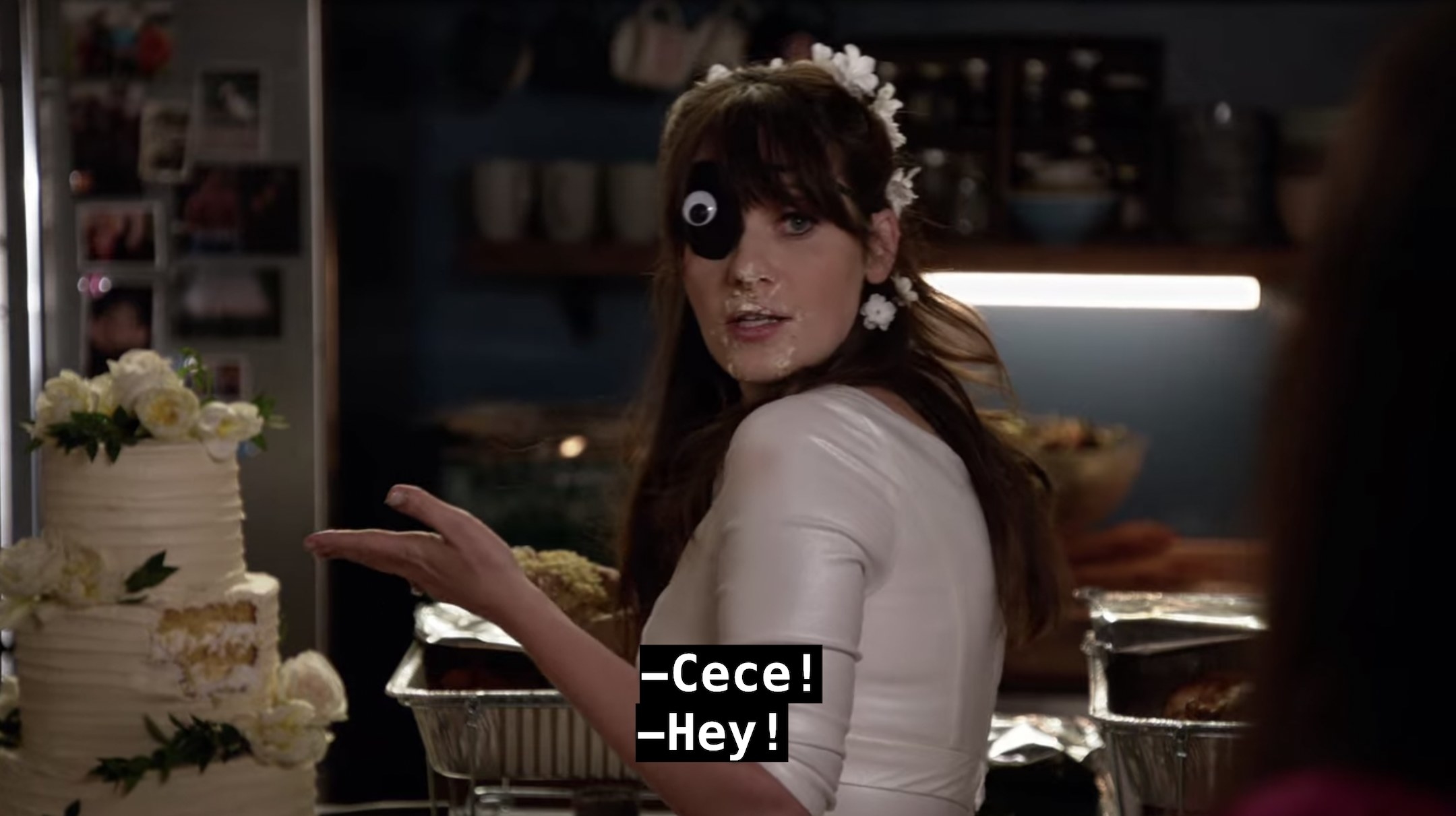 Jess turns around, wearing an eye patch with a googly eye on it, holding a piece of the middle of her wedding cake, with cake all around her mouth, and says Cece