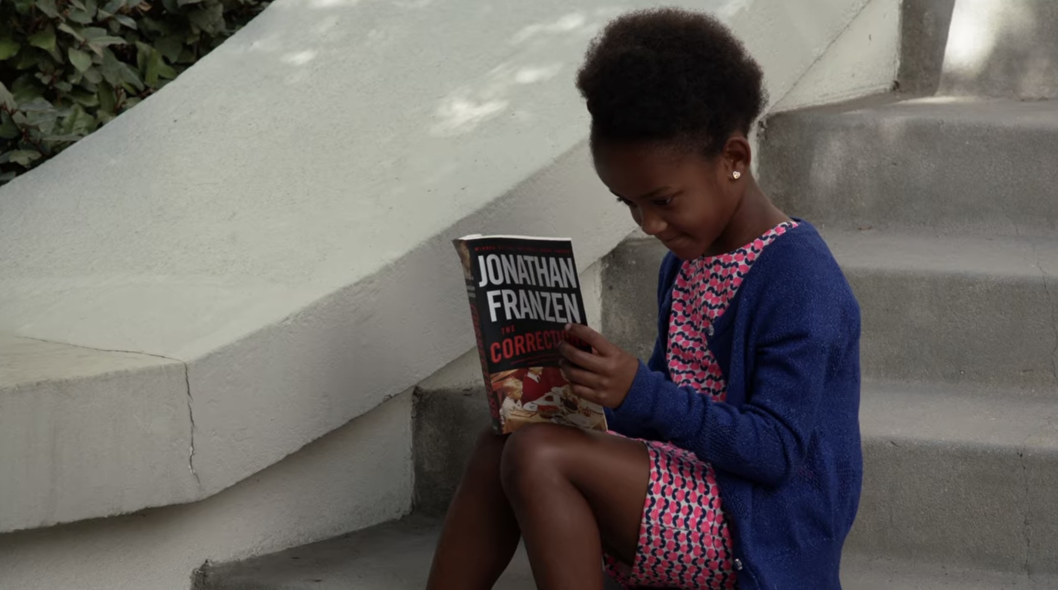 We see a little girl reading a Jonathan Franzen novel