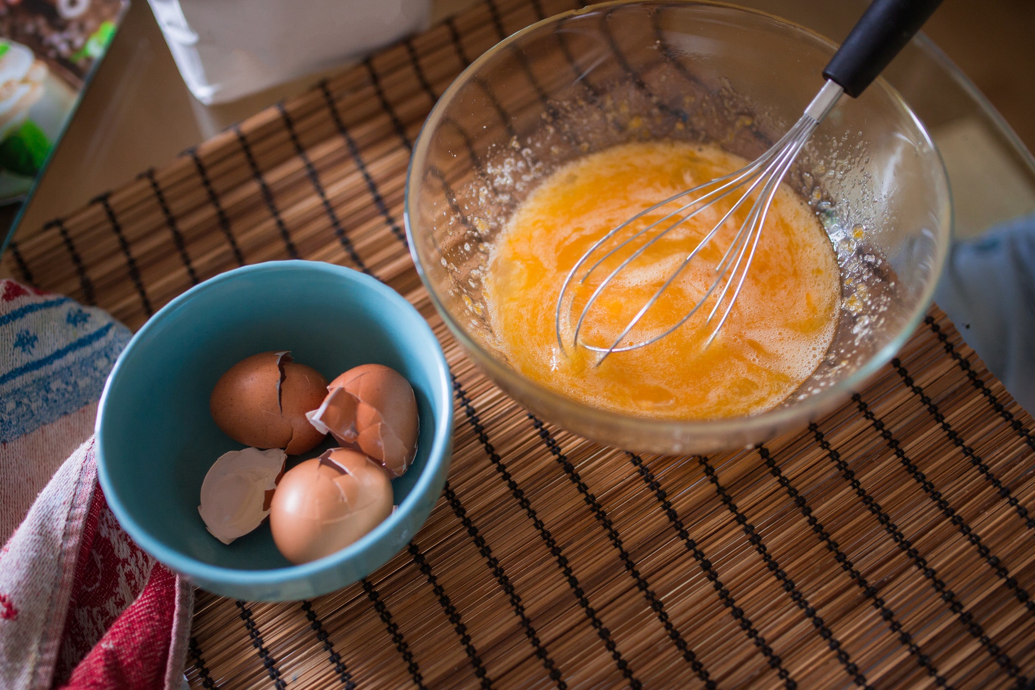 Beaten eggs in a glass bowl on the table.
