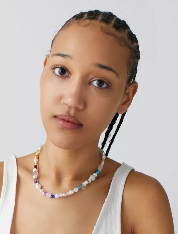 A person wearing the necklace against a plain backdrop