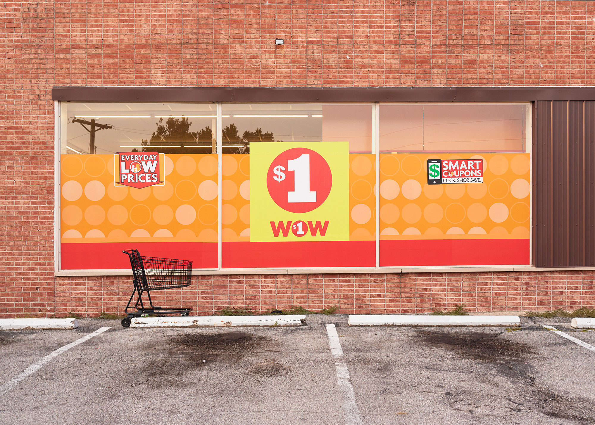 A shopping cart in front of a sign that says $1 Wow in a parking lot