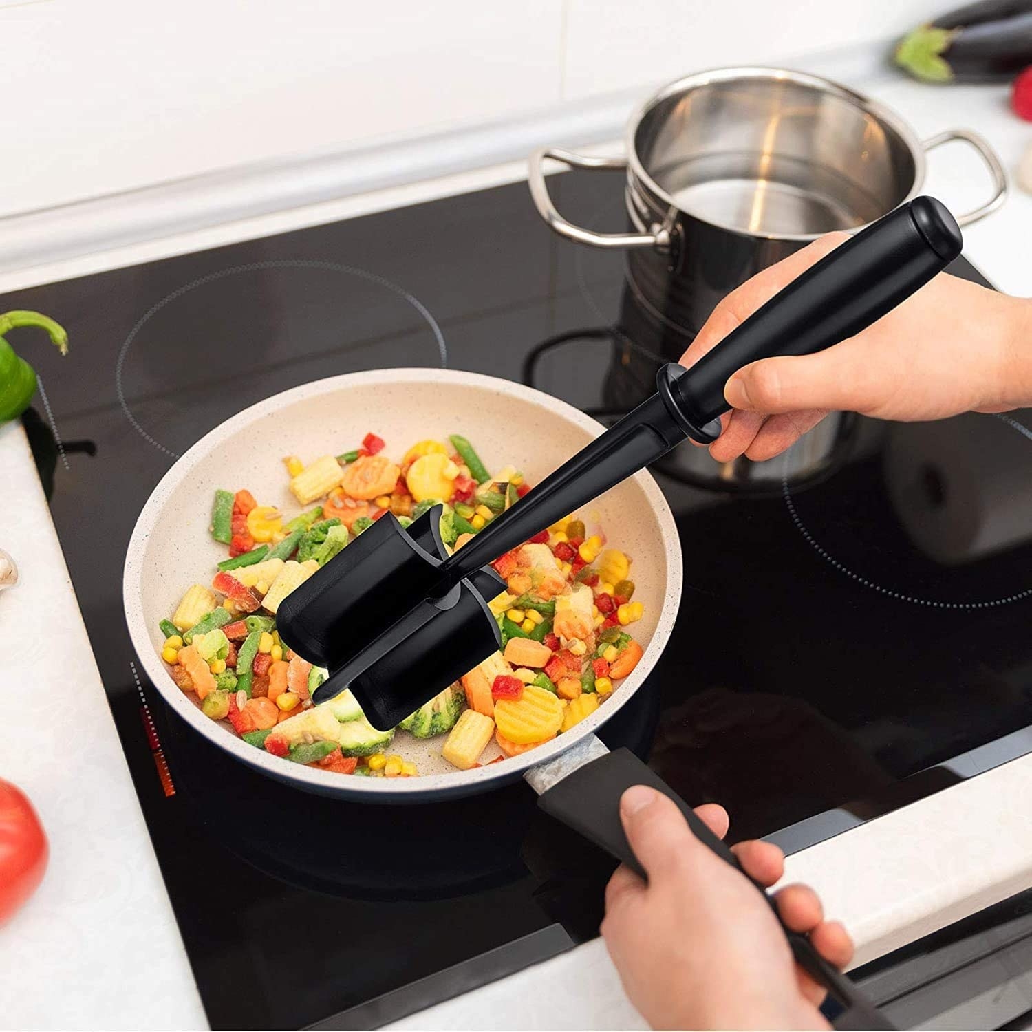 a person using the masher in a pan full of vegetables