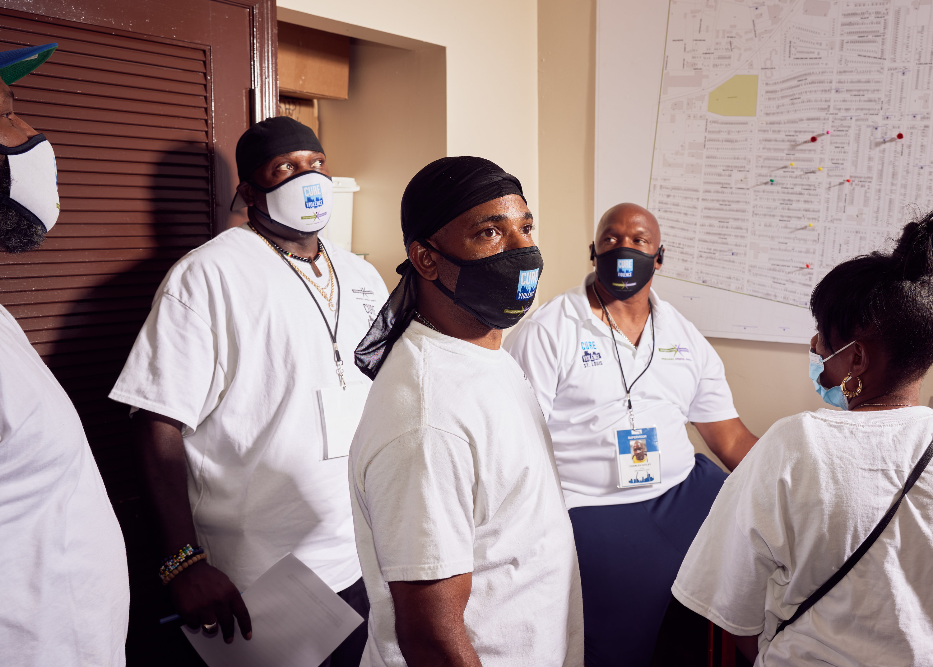 A group of people wearing masks in front of a map