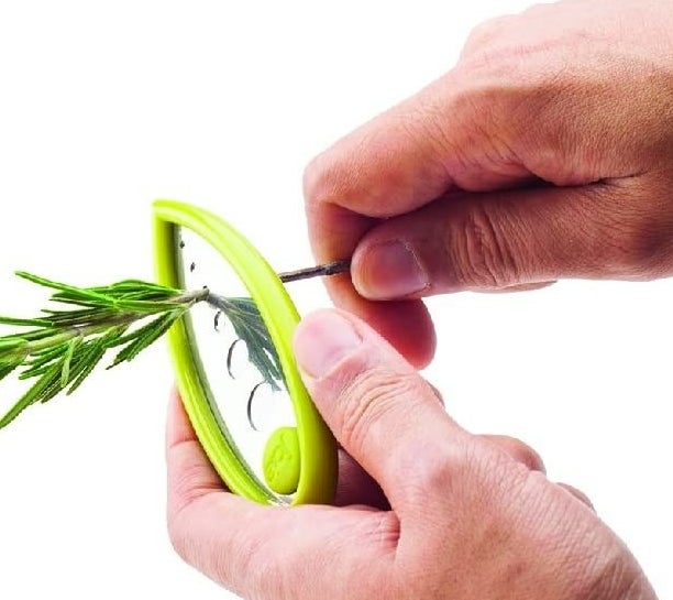 a person using the tool to de-stem a sprig of rosemary