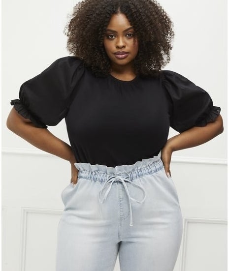 Model wearing black tee with light wash jeans