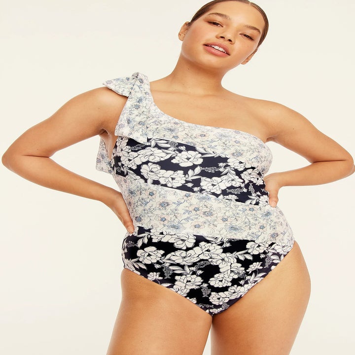 model wearing a one shoulder one-piece swimsuit with blue and white floral design