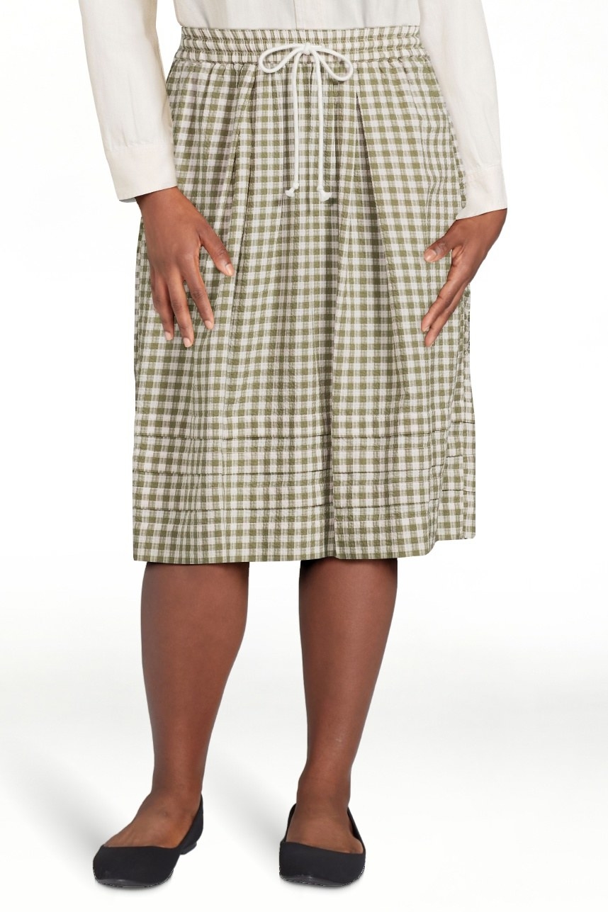 Model wearing green gingham skirt with black shirts and white top