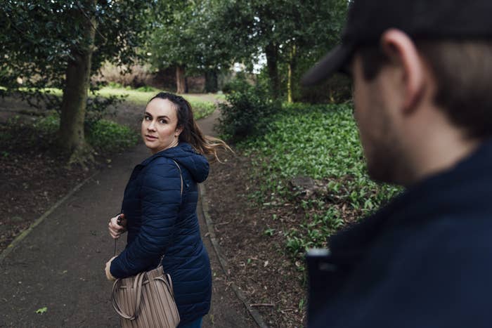 a woman looking back as she gets away from a stranger in a park