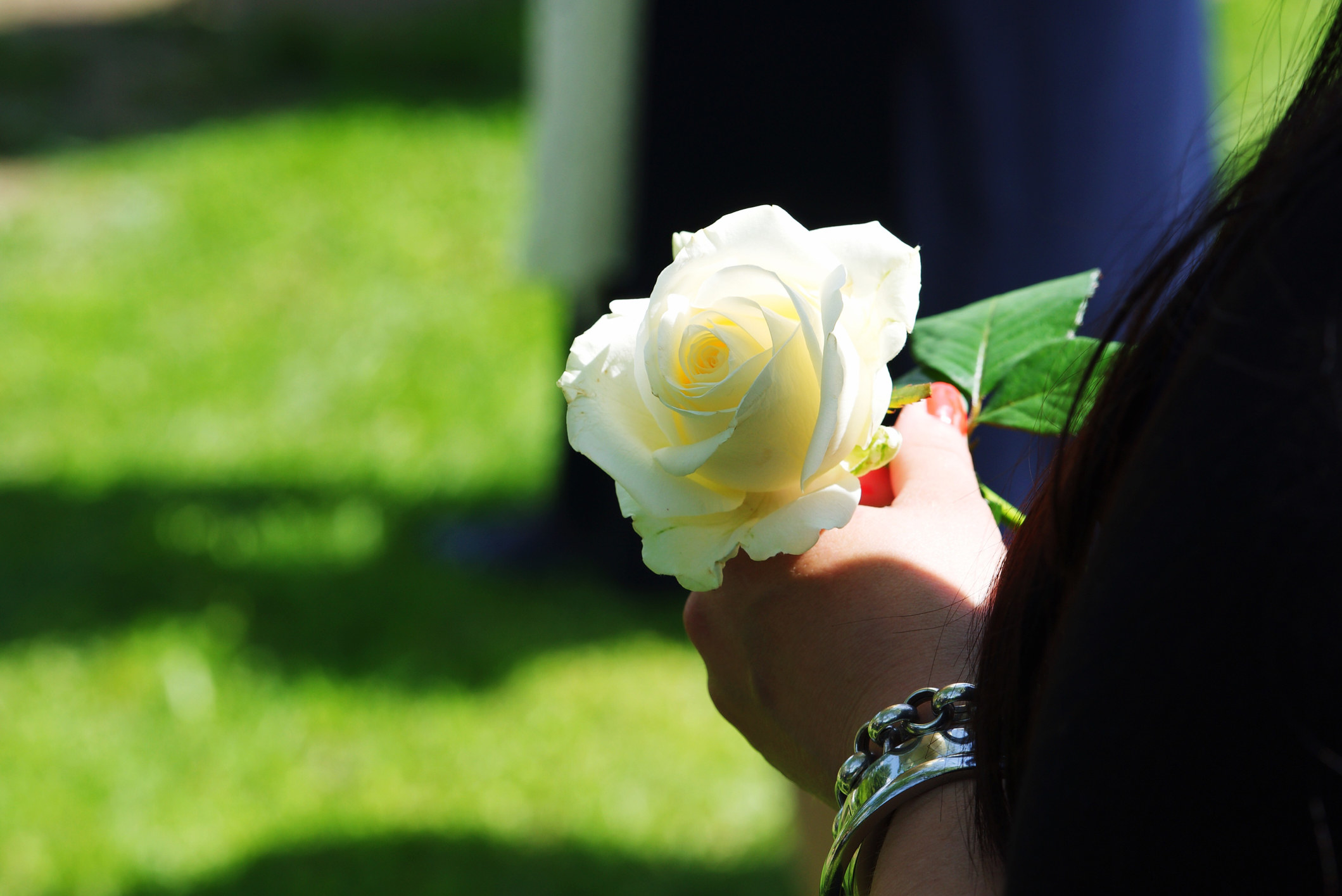 A woman holding a white flower at a funeral.