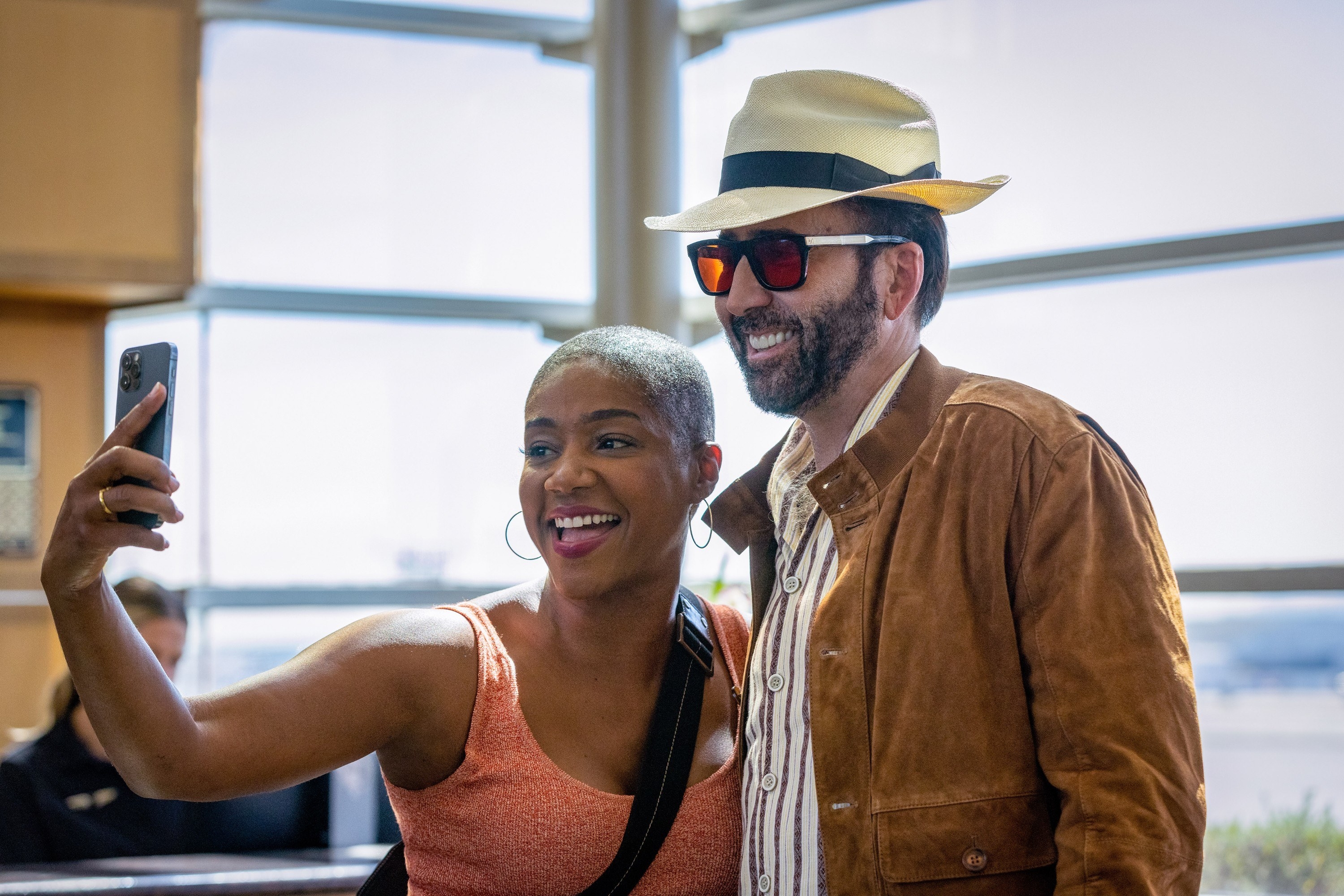 A closeup of Nicolas in character taking a selfie with a fan played by Tiffany Haddish